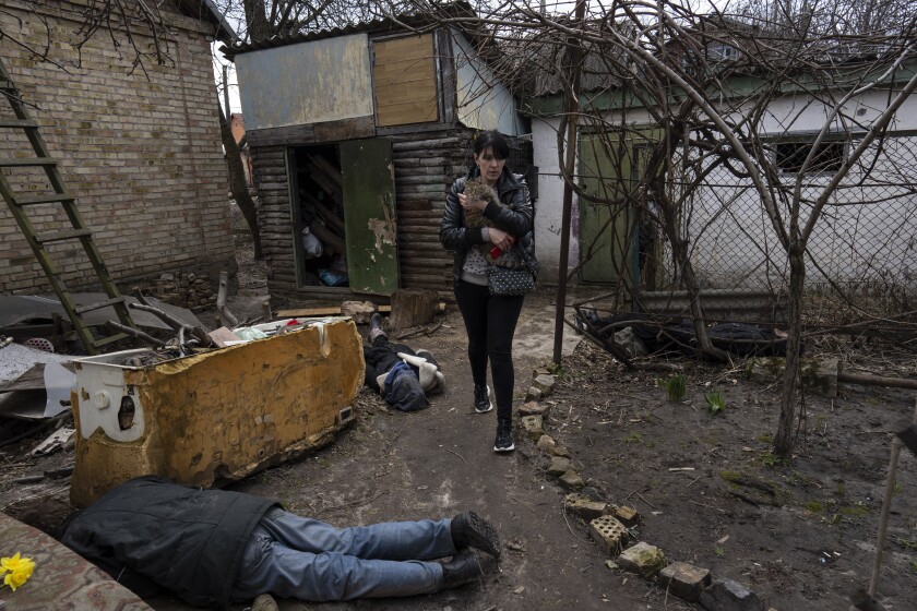 FILE - Ira Gavriluk holds her cat as she walks next to the corpses of her husband and her brother, who were killed in Bucha, on the outskirts of Kyiv, Ukraine, Monday, April 4, 2022. (AP Photo/Rodrigo Abd, File)