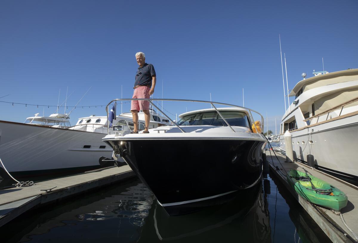 Bill Wolf stands at the front of a boat in a marina.