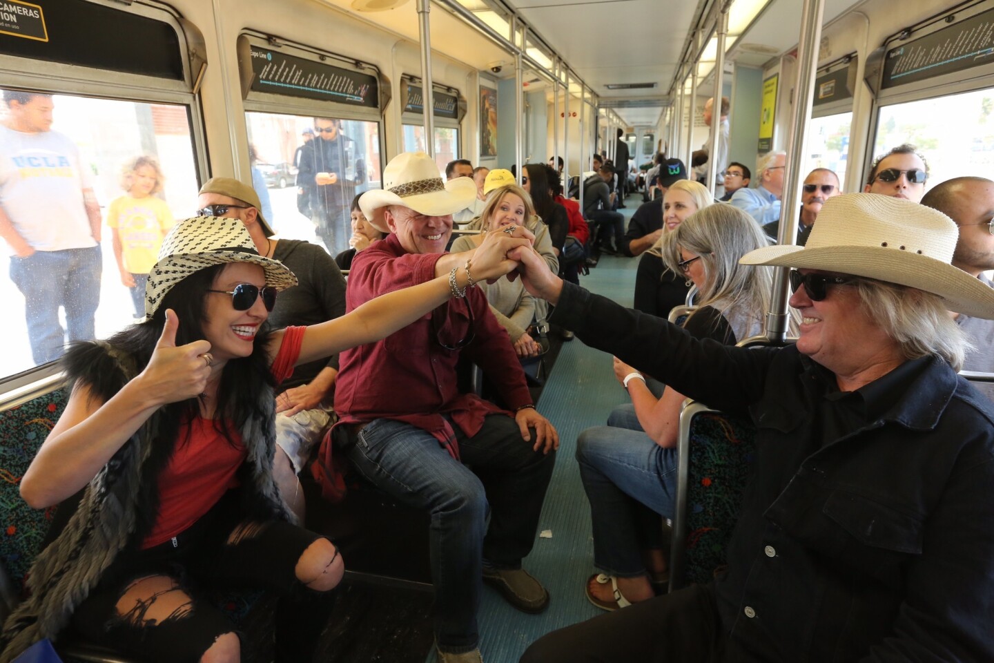 From left; Kat Herrera, Benjamin Hutto, and Brian O' Brien, all friends from Malibu, celebrate as the Expo Line leaves Santa Monica Station. They were heading to Los Angeles to celebrate O' Brien's 65th birthday.