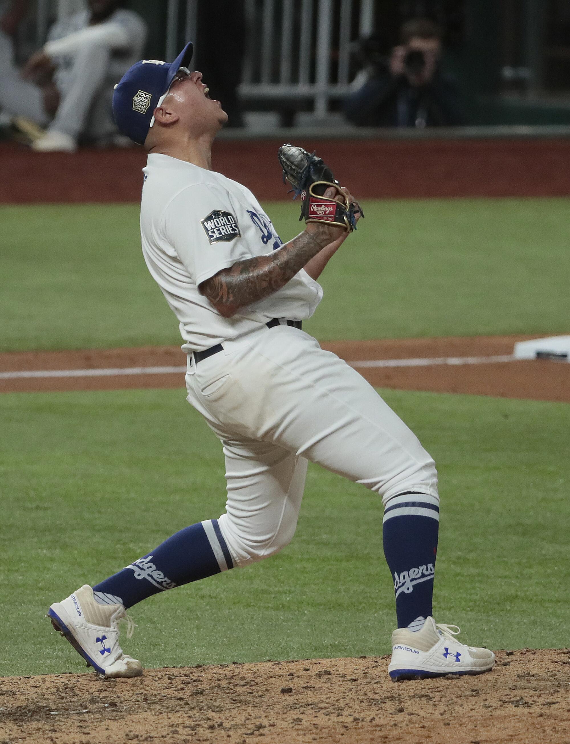  Julio Urías clenches his fists and yells skyward on the pitcher's mound.