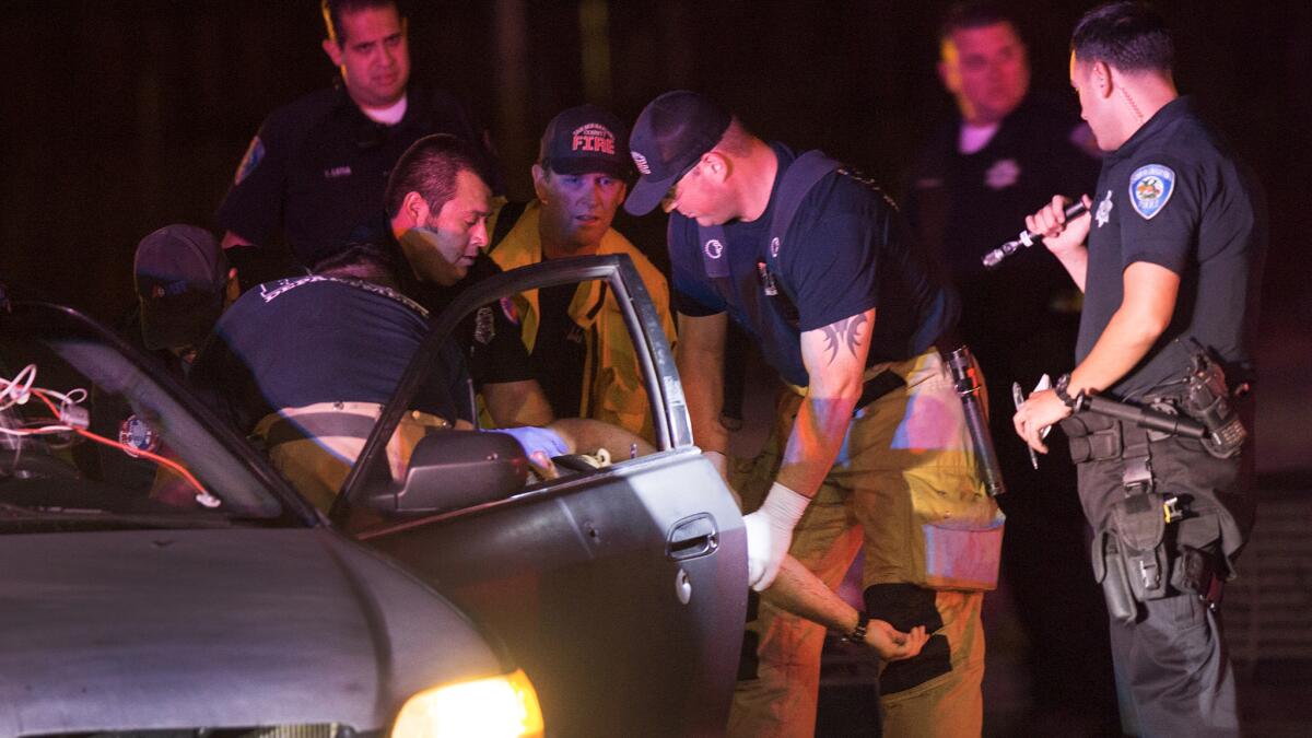 Firefighters and paramedics extricate Alejandro Herrera, 28, from his car after he was shot while sitting at an intersection on Aug. 10 in San Bernardino. Herrera died at the hospital.