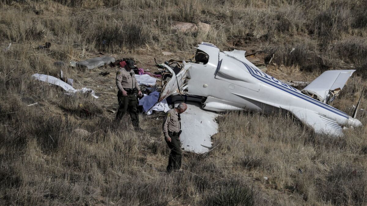 L.A. County sheriff's deputies inspect the site where a small aircraft crashed Sunday, killing four people in a remote area near Agua Dulce.