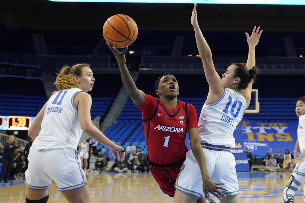 Arizona guard Shaina Pellington, center, shoots between UCLA forward Emily Bessoir, left, and guard Gina Conti.