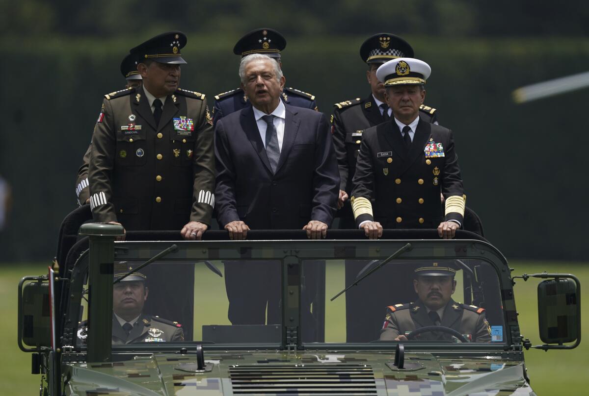 FILE - Mexico's President Andres Manuel Lopez Obrador, center, Defense Secretary Luis Cresencio Sandoval, left, and Naval Commander Jose Rafael Ojeda ride in a military vehicle during a parade introducing the new army commander, in Mexico City, Aug. 13, 2021. Mexico launched its army-run airline on Dec. 26, 2023, another role that López Obrador has given to Mexico’s armed forces. (AP Photo/Fernando Llano, File)