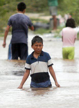 A boy tries to make his way through a flooded street in Bacalan, Chetumal, in the Yucatan peninsula, where Hurricane Dean swept through and left extensive damage but few injuries.