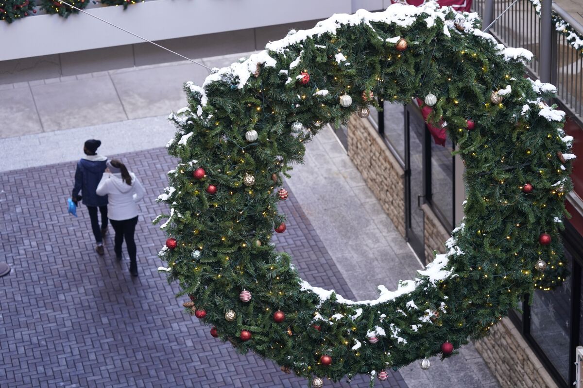 Aerial view of two people walking beneath a hanging Christmas wreath