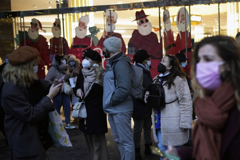 Pedestrians wear masks to prevent the spread of the COVID-19 as they walk past a store decorated as part of Christmas lightings, in Paris, Monday, Dec. 6, 2021. The new potentially more contagious omicron variant of the coronavirus popped up in more European countries just days after being identified in South Africa, leaving governments around the world scrambling to stop the spread. (AP Photo/Christophe Ena)