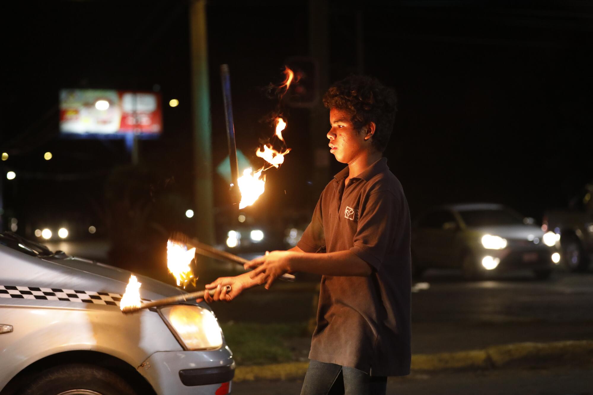 A boy juggles fire sticks in an intersection in Managua, Nicaragua