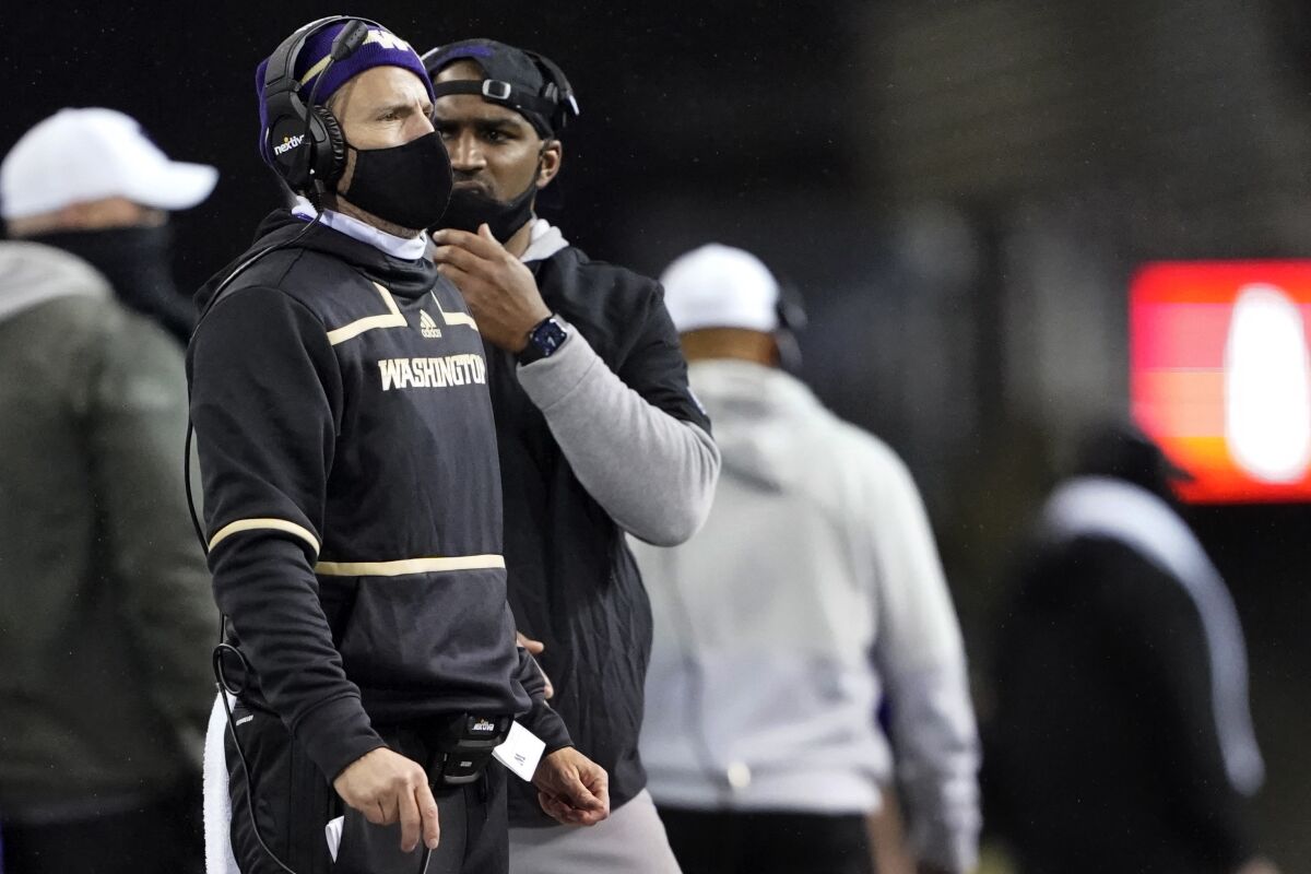 Washington inside linebackers coach Bob Gregory, left, wears a headset on the sideline during the team's NCAA college football game against Oregon State on Nov. 14, 2020, in Seattle. Gregory, now defensive coordinator, will lead Washington as interim coach against Arizona State on Saturday, Nov. 13, in Seattle after coach Jimmy Lake was suspended for one game without pay for making physical contact with one of his players on the sideline during a loss to Oregon on Nov. 6. (AP Photo/Ted S. Warren)