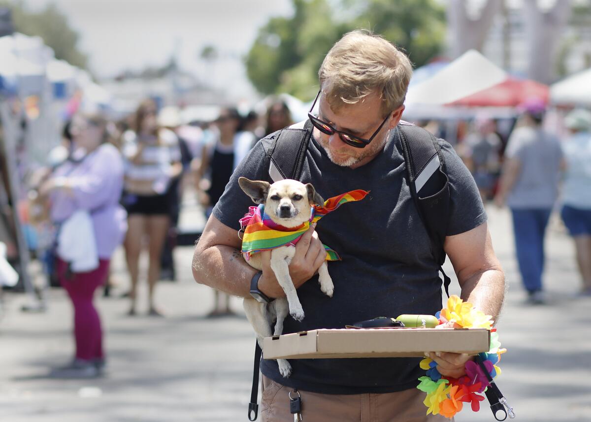 Sean Giorgianni of Redlands carries his daughter's chihuahua adorned with a rainbow scarf