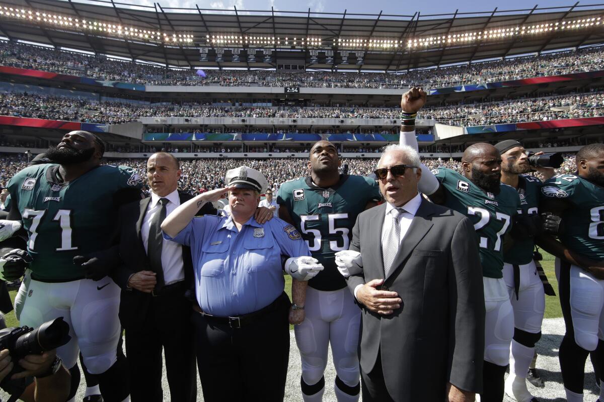 Philadelphia Eagles players and owner Jeffrey Lurie link arms during the national anthem before a Sept. 24 game against the New York Giants in Philadelphia. Malcolm Jenkins, next to Lurie, raises his fist. (Matt Rourke / AP)