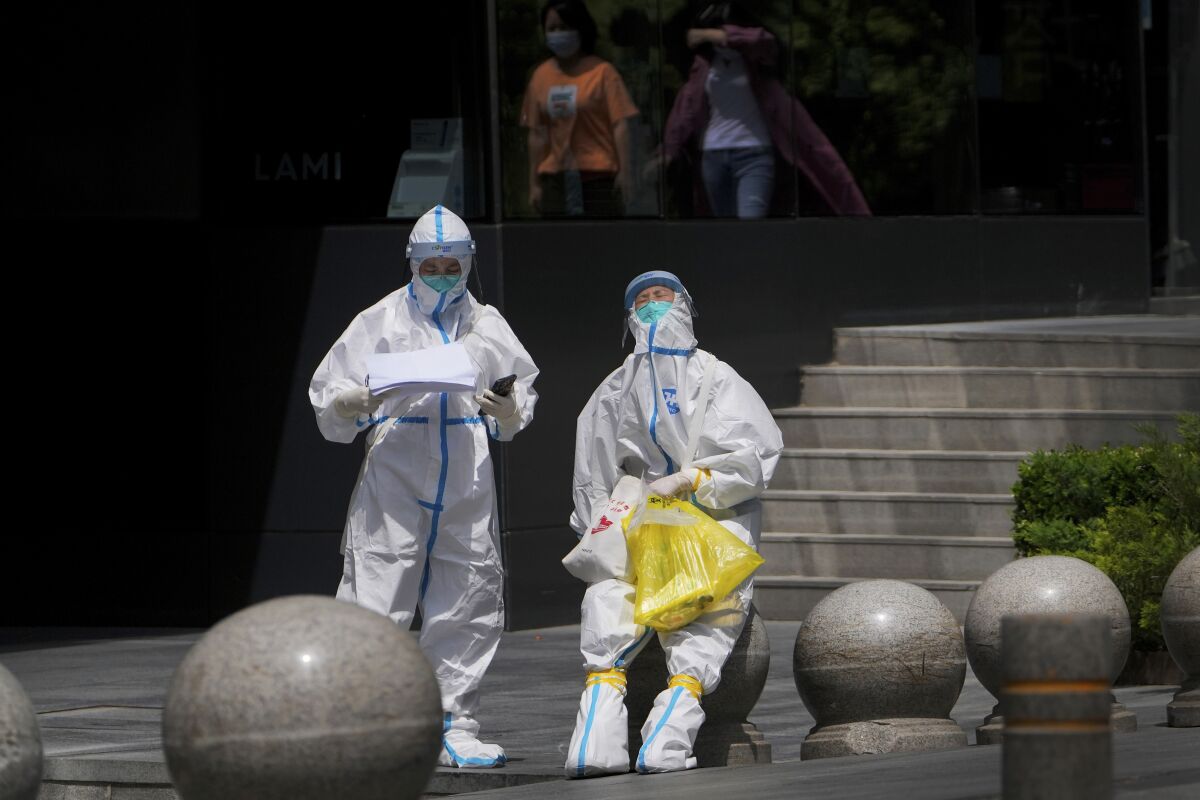 Medical workers in protection suits take a rest after conducting COVID tests for residents near a commercial office complex on Thursdays, May 12, 2022, in Beijing. (AP Photo/Andy Wong)