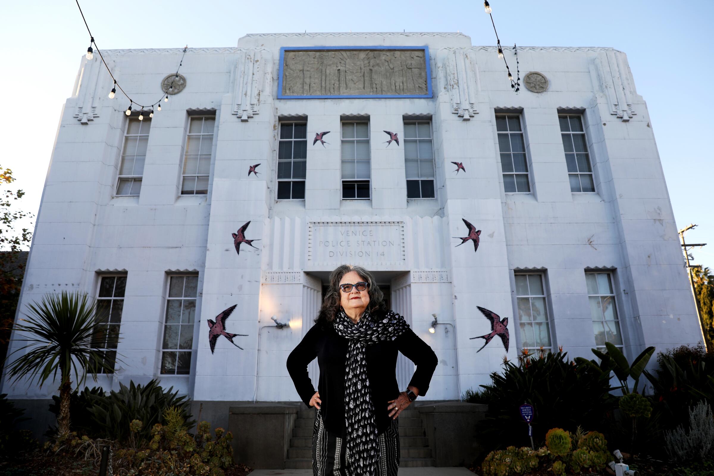 Artist Judy Baca, dressed in black, stands before the Art Deco building that houses SPARC in Venice.