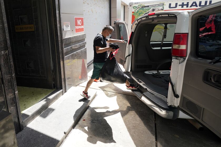 A man loads the back of a van with a bag from inside the Chinese Consulate Thursday, July 23, 2020, in Houston. China says the U.S. has ordered it to close its consulate in Houston in what it called a provocation that violates international law. (AP Photo/David J. Phillip)