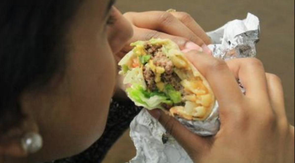 Fotografía del 10 de marzo de 2017 de una persona comiendo un "burgrito", una combinación de burrito mexicano y hamburguesa con papas fritas que se ha convertido en la última moda culinaria que triunfa en Nueva York. TEFE/Khrystyna kinson/Archivo