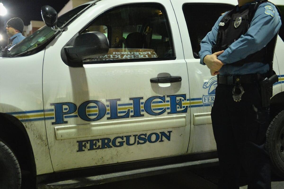 A Ferguson, Mo., police officer stands watch during a protest Wednesday after the Justice Department announced it would not charge ex-Ferguson Police Officer Darren Wilson in the shooting death of 18-year-old Michael Brown.