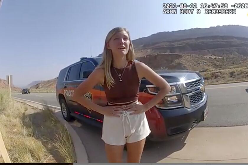 FILE- In this image taken from police body camera video provided by The Moab Police Department, Gabrielle "Gabby" Petito talks to a police officer after police pulled over the van she was traveling in with her boyfriend, Brian Laundrie, near the entrance to Arches National Park on Aug. 12, 2021. The family of Petito filed a notice of claim Monday, Aug. 8, 2022, of plans to file a wrongful death lawsuit against the tourist town of Moab, Utah, over police officers' handling of an encounter with Petito and her boyfriend weeks she was found dead in Wyoming. (The Moab Police Department via AP, File)