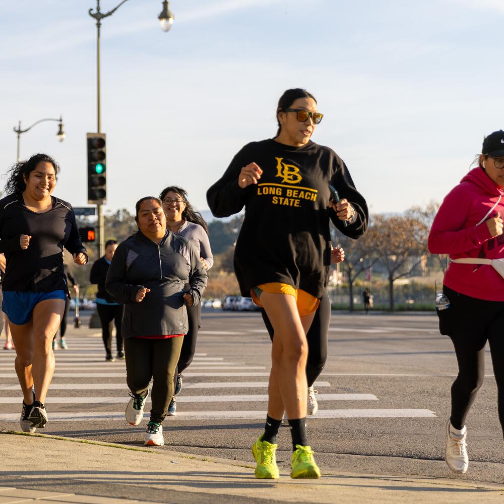 Women run across a crosswalk.