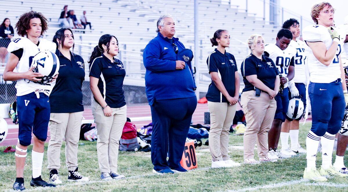 Venice football coach Angelo Gasca holds his right hand over his heart during the national anthem before a game.