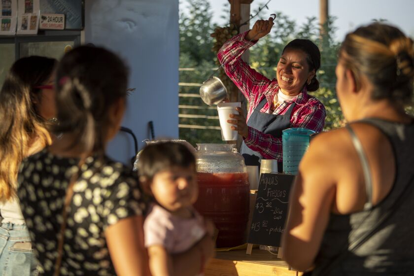 Farmer Liset Garcia pours a cup of aguas frescas at her Sweet Girl Farms stand on Thursday, July 1, 2021 in Reedley, CA.