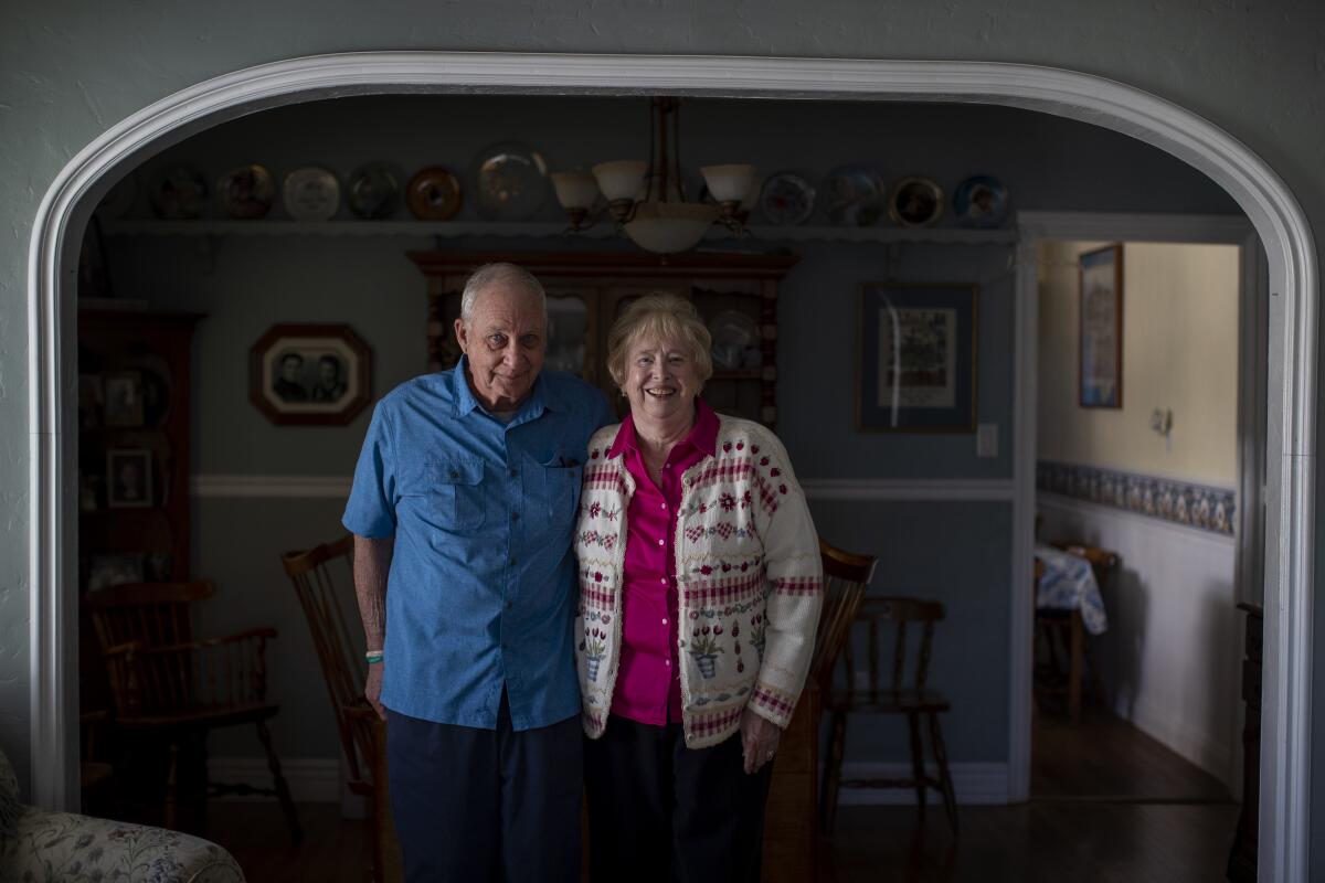 A couple poses for a photo inside their home.
