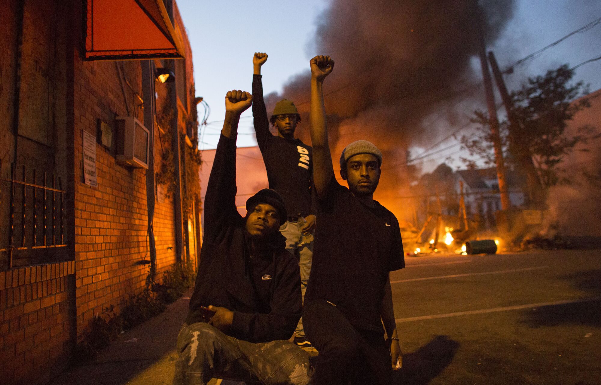 Protesters hold fist in the air in front of a burning car lot on May 29, 2020.