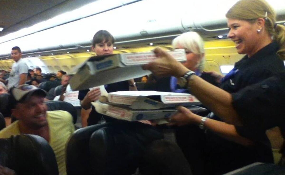 A Frontier Airlines flight attendant hands out pizza Monday to passengers aboard a Denver-bound flight that had been diverted to Cheyenne, Wyo.