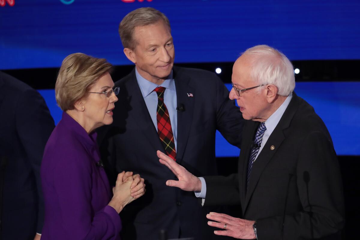 Elizabeth Warren and Bernie Sanders speak as Tom Steyer looks on after the Democratic presidential primary debate Tuesday night in Des Moines.