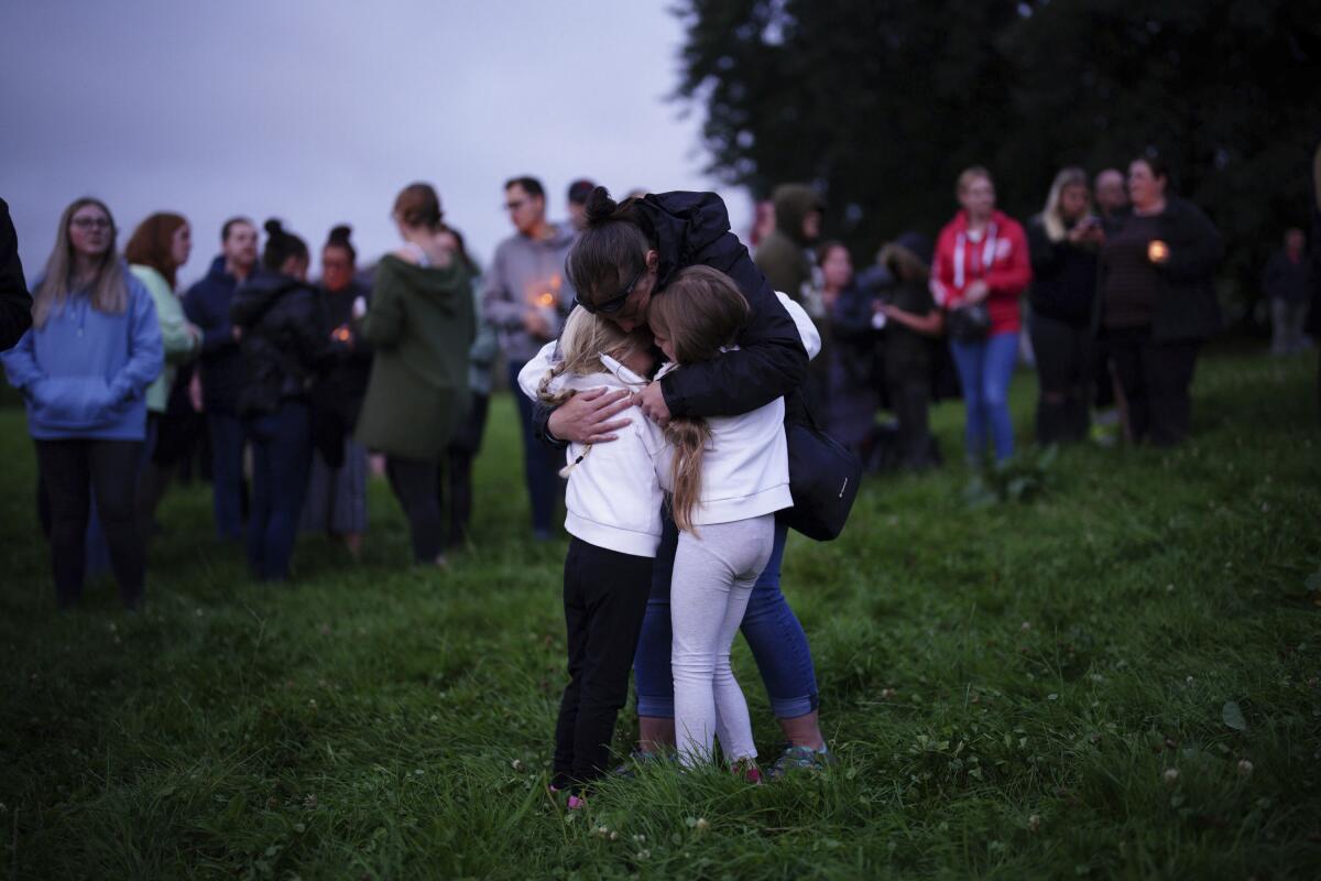 A woman consoles children during an outdoor vigil for the victims of a mass shooting