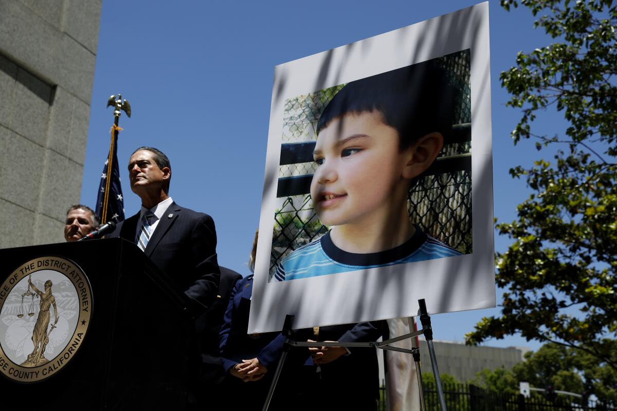 Orange County Dist. Atty. Todd Spitzer stands next to a giant photo of Aiden Leos.