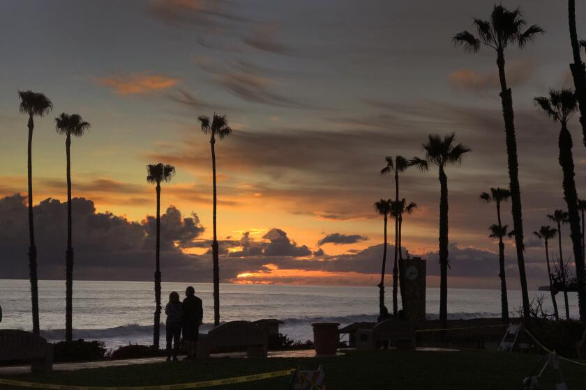 SAN CLEMENTE, CA -- WEDNESDAY, APRIL 8, 2020: A couple takes in a sunset together near the San Clemente pier after San Clemente closed it's beaches to help curb the spread of the coronavirus in San Clemente, CA, on April 8, 2020. Officials said the Orange County Sheriff's Department, Marine Safety, Code Enforcement and Park Rangers will increase monitoring and people who do not comply could be cited. (Allen J. Schaben / Los Angeles Times)