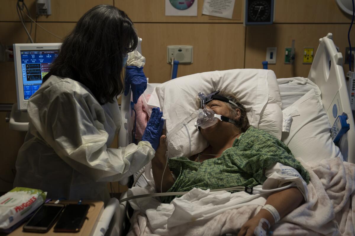 Becky Gonzalez, left, visits longtime friend Mary Lou Samora, a 71-year-old COVID-19 patient.