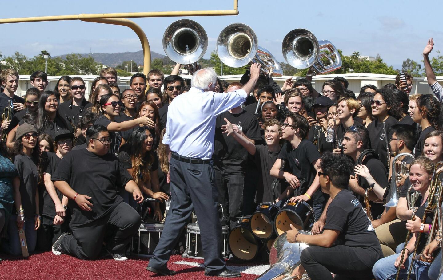 After speaking at a rally at the Rancho Buena Vista High School football stadium, Democratic presidential candidate Bernie Sanders waves to members of Rancho Buena Vista's marching band, called Rhythm of the Ranch, after he posed for a picture with them