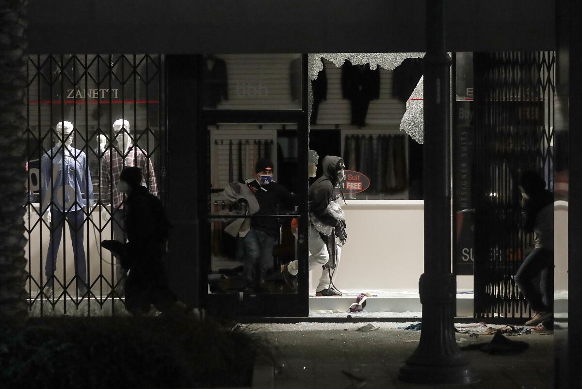 Looters ransack a clothing store on Pine Avenue in Long Beach on Sunday.