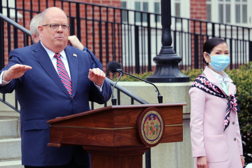 FILE - In this Monday, April 20, 2020 file photo, Maryland Gov. Larry Hogan speaks at a news conference in Annapolis, Md., with his wife, Yumi Hogan, right, where the governor announced Maryland has received a shipment from a South Korean company to boost the state's ability to conduct tests for COVID-19 by 500,000. Maryland auditors have found Gov. Larry Hogan’s administration failed to follow state procurement regulations when it bought 500,000 COVID-19 tests from a South Korean company last year. The audit released Friday, April 2, 2021 also said the first batch of tests that later had to be replaced at additional $2.5 million cost had not been authorized by the U.S. Food and Drug Administration. (AP Photo/Brian Witte, File)