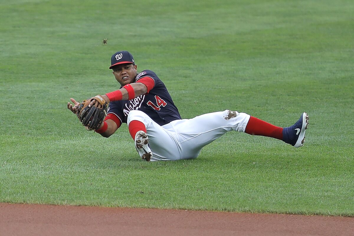 Washington Nationals second baseman Starlin Castro is unable to field a ground ball by Baltimore Orioles' Bryan Holaday during the sixth inning in the continuation of a suspended baseball game, Friday, Aug. 14, 2020, in Baltimore. The first part of the game was suspended on Aug. 9, when the groundskeepers had technical difficulties with the infield tarp in the sixth inning during a rain delay, causing the infield to become too wet and muddy to play. Orioles' Dwight Smith Jr. scored on the play. (AP Photo/Julio Cortez)