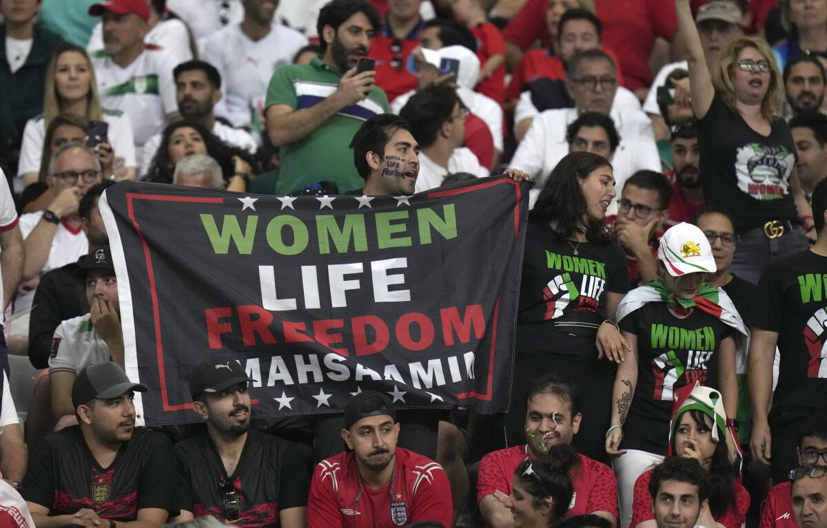 Iranian soccer fan holds up sign reading Woman Life Freedom Masha Amini prior to the World Cup group B.