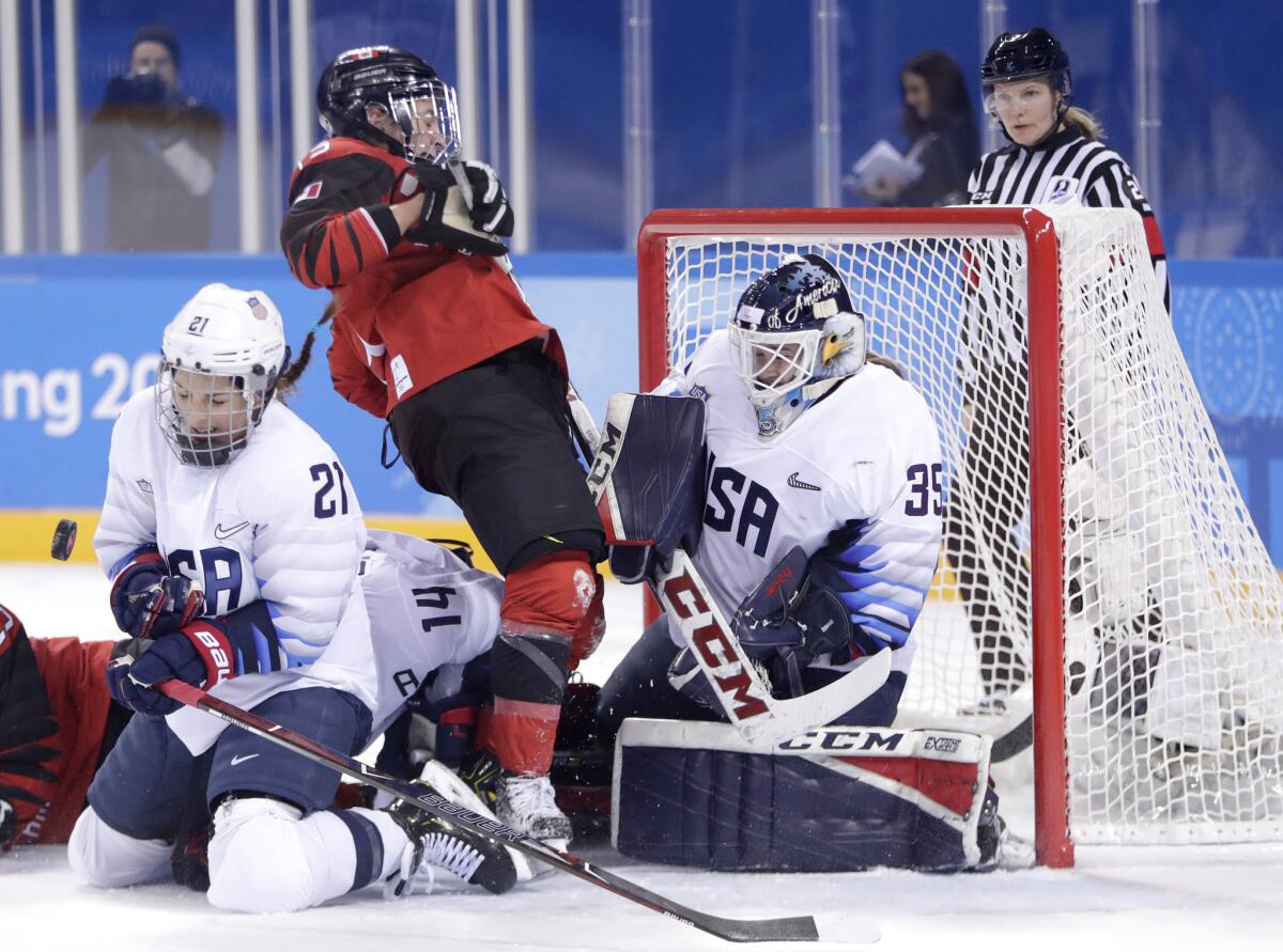 Hilary Knight blocks a shot as goalie Maddie Rooney, right, protects her net against Canada.