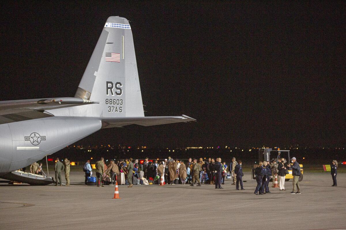 Families evacuated from Kabul, Afghanistan, walk past a U.S Air Force plane that they arrived on.