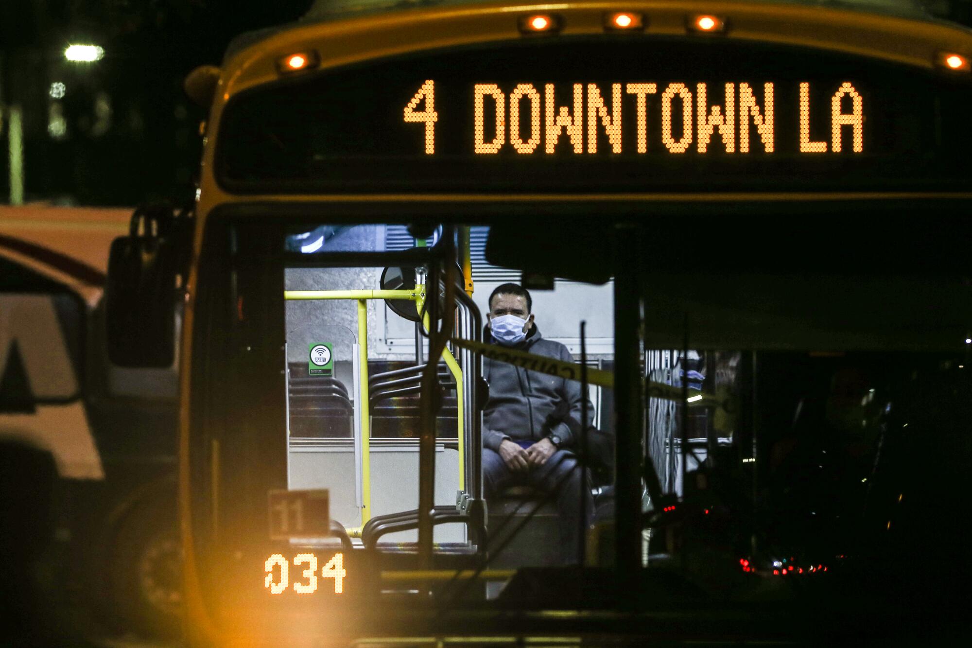 A masked commuter rides the bus in downtown L.A. 