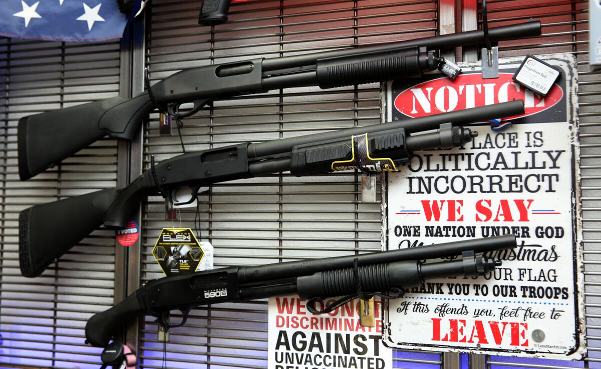 Three shotguns on display in a gun store with decorative several signs