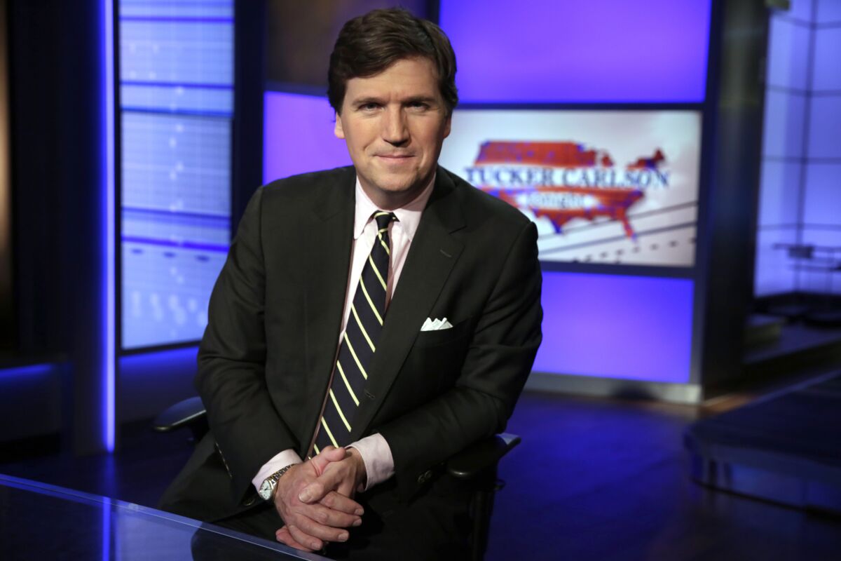 FILE - In this March 2, 20217, file photo, Tucker Carlson, host of "Tucker Carlson Tonight," poses for photos in a Fox News Channel studio in New York. A steady criticism of COVID vaccine mandates by figures on Fox News has drawn attention to its own company's stringent rules on the topic — even from President Joe Biden. Carlson devoted nearly the first 20 minutes of his show on Sept. 15, 2020, to Biden's COVID efforts, saying the rules require people to submit to being bullied. (AP Photo/Richard Drew, File)