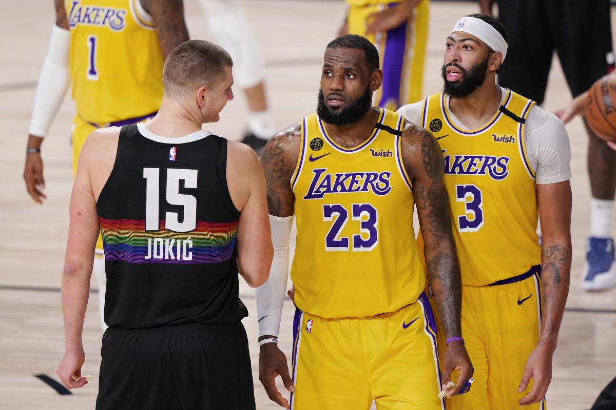 Nuggets center Nikola Jokic, left, talks to Lakers stars LeBron James, center, and Anthony Davis during a game.