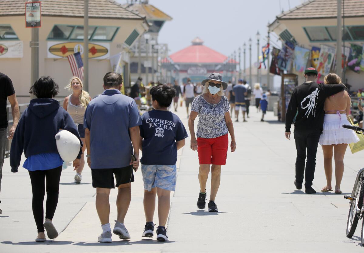 People walk the Huntington Beach Pier in June 2020.
