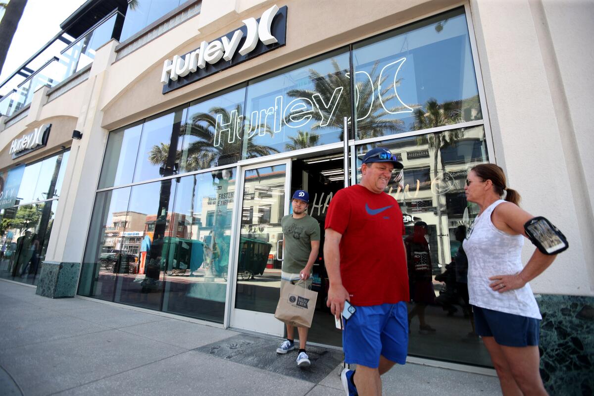 With his parents, Gary and Patti McElmurry, in front of him, Wyatt McElmurry exits the Hurley store on Main Street with a T-shirt, socks and swimming trunks on Friday, the first day the store reopened for business in more than four weeks.