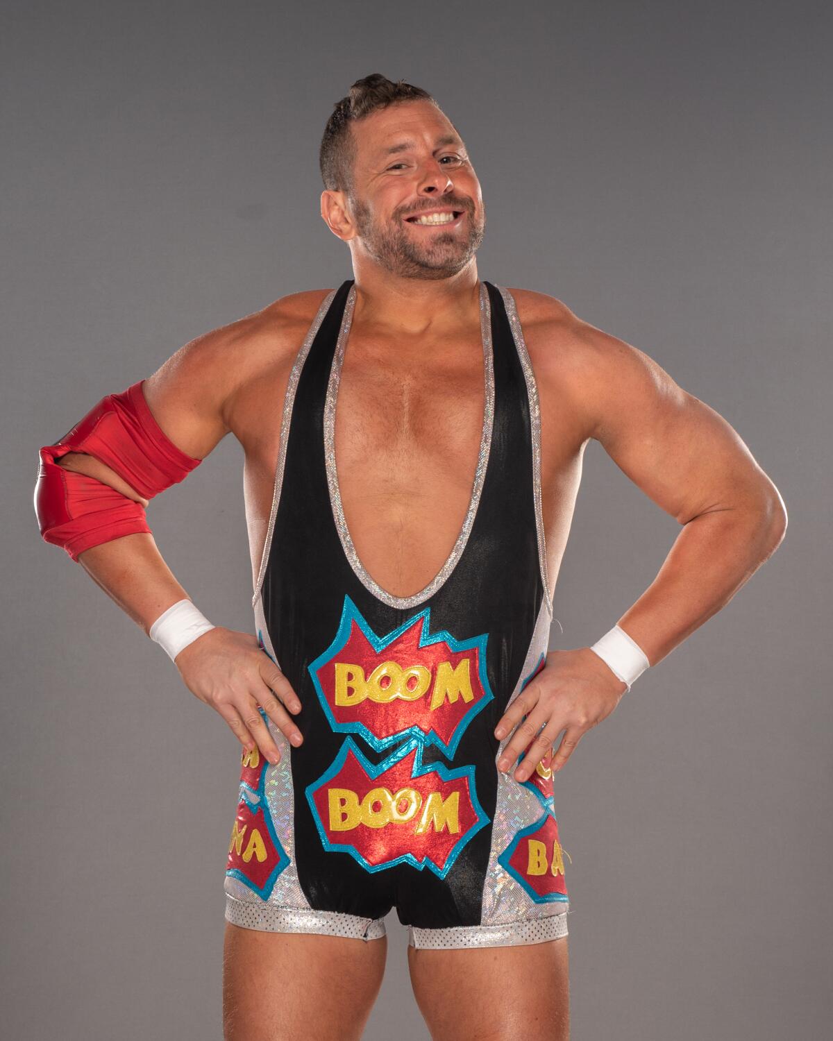 A smiling wrestler whose outfit has the word "boom" printed on it