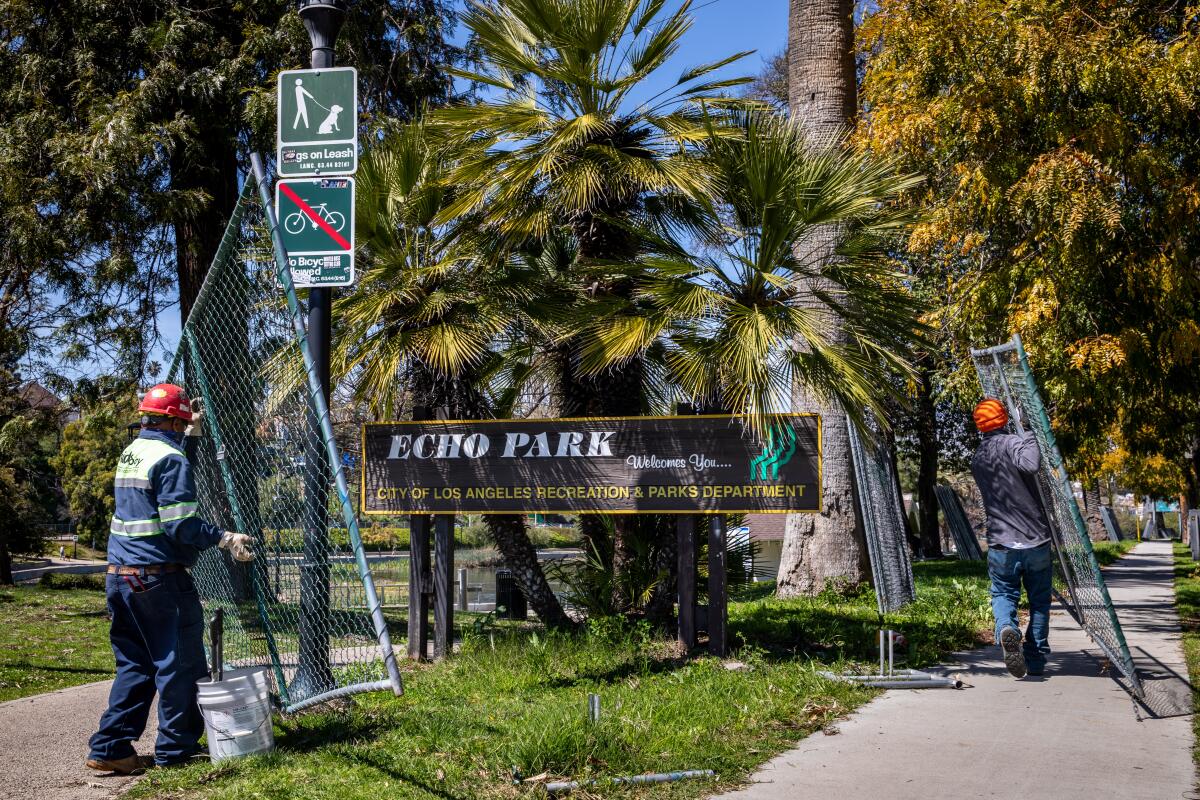 Workers take down the fence around Echo Park Lake in Los Angeles, after about two years of surrounding the park. 