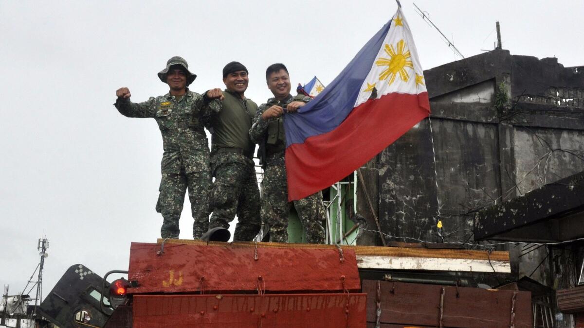 Filipino soldiers atop a military tank celebrate in the ruined city of Marawi, southern Philippines, on Oct. 17, 2017.