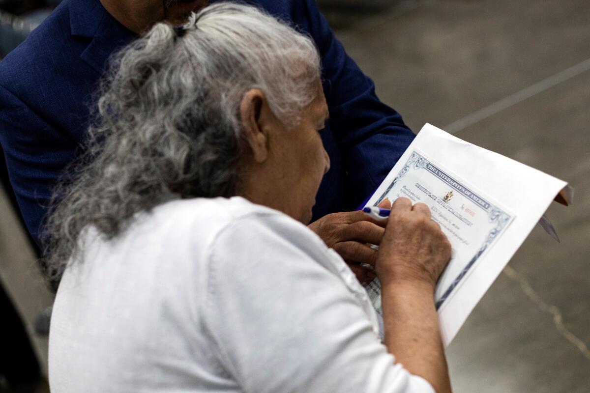 Cientos de personas asisten a una ceremonia de naturalización, se ve  a una mujer