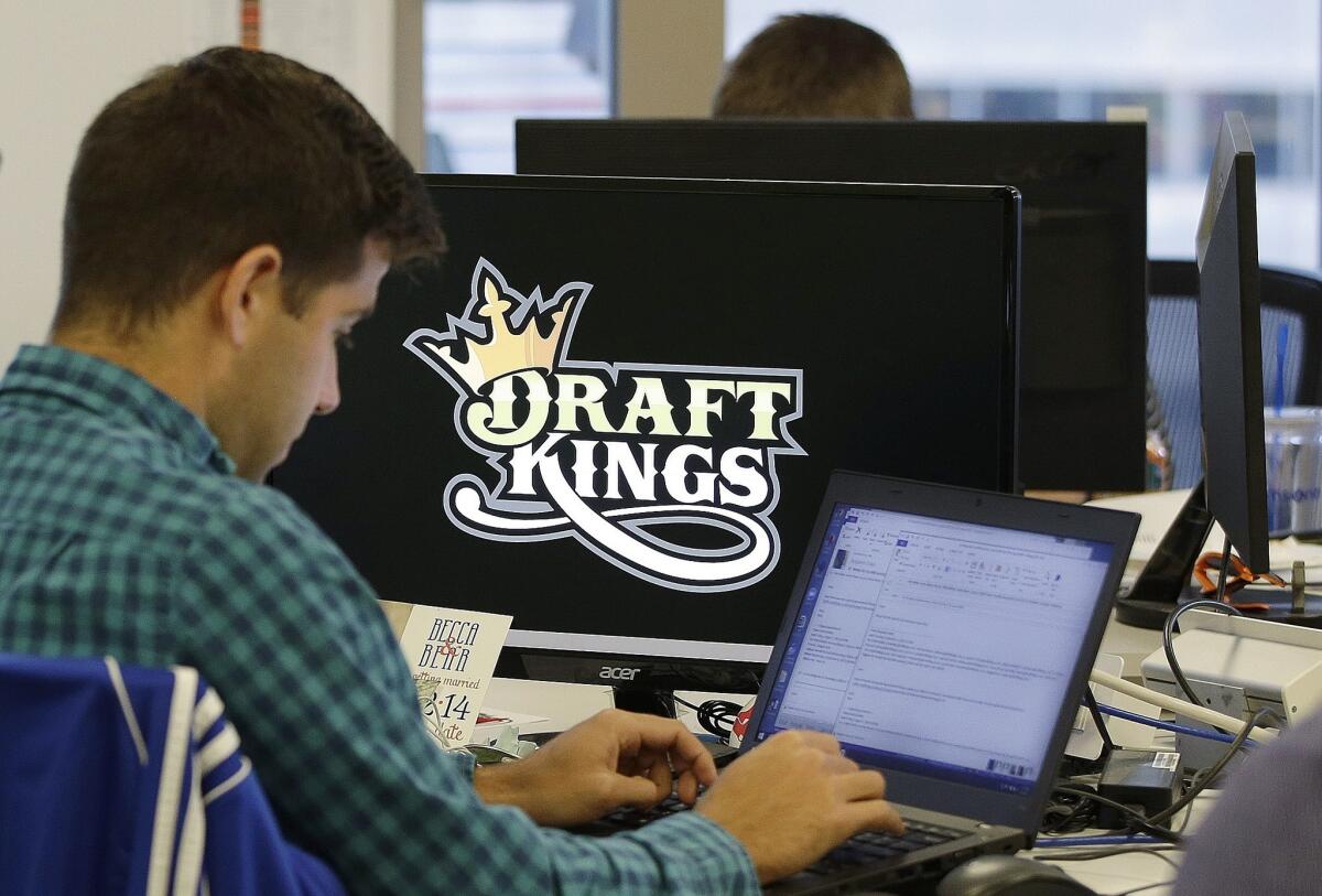 In this file photo, Bear Duker, a marketing manager for strategic partnerships at DraftKings, works at company headquarters in Boston. Daily fantasy sports rivals DraftKings and FanDuel have agreed to merge.